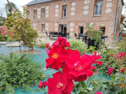 a bunch of red flowers in front of a building at Gite La Fleuv'Yeres in Villy-sur-Yères
