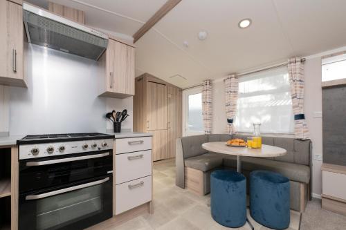 a kitchen with a stove and a small table at Tencreek Holiday Park in Looe