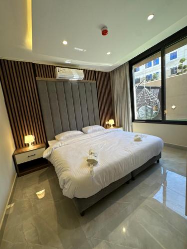 a bedroom with a large white bed with two lamps at Chic Apartments For Rent ave0-1 in Umm Uthainah