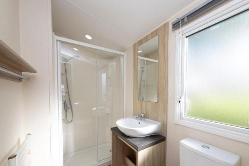 a bathroom with a white sink and a shower at Tencreek Holiday Park in Looe