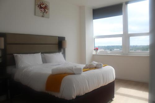 a bedroom with a bed with white sheets and two windows at Flat 405 One bedroom apartment in Birmingham