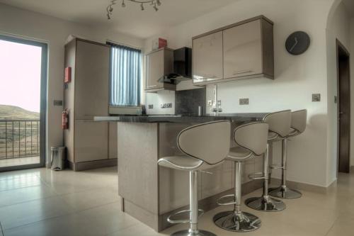 a kitchen with three bar stools at a counter at SeaHorse Penthouse in Żebbuġ
