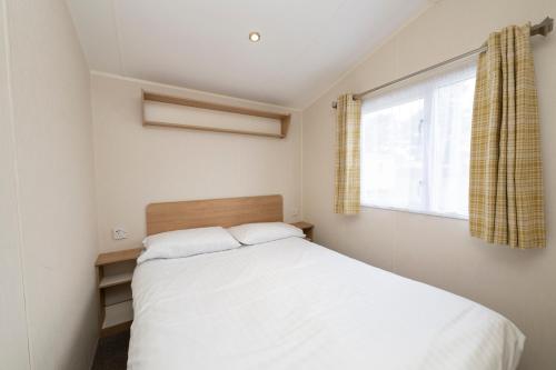 a bedroom with a white bed and a window at Tencreek Holiday Park in Looe