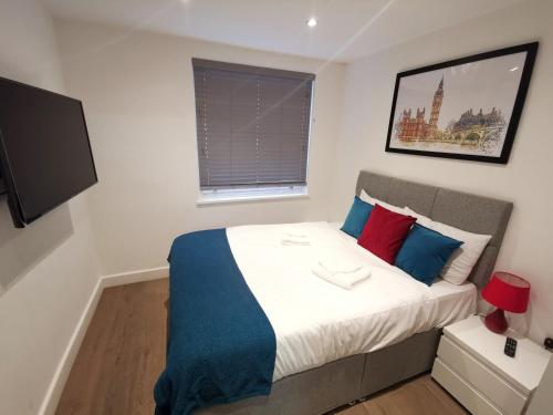 a bedroom with a large bed with blue and red pillows at City Prime Apartments in London
