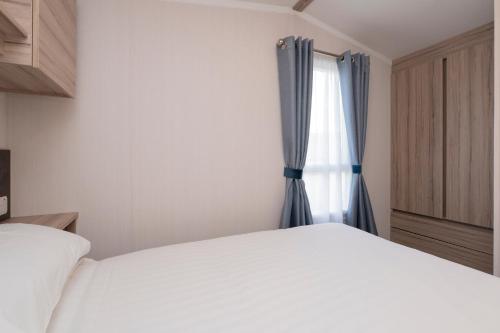 a bedroom with a white bed and a window at Tencreek Holiday Park in Looe