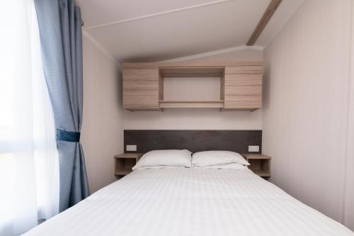 a small bedroom with a bed and a window at Tencreek Holiday Park in Looe