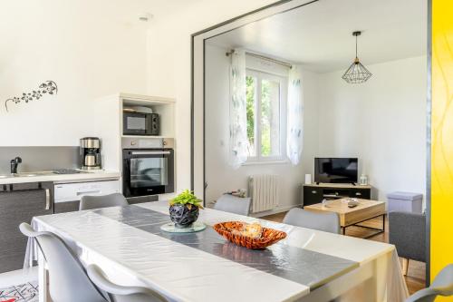 une cuisine et un salon avec une table et des chaises blanches dans l'établissement Maison Ker Morin La Gacilly, à La Gacilly