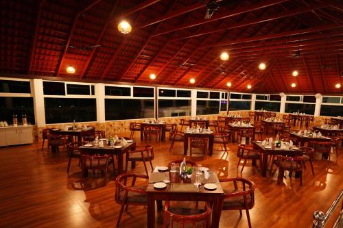 uma sala de jantar com mesas e cadeiras em um restaurante em Coorg Orange Blossom Resort and Spa em Suntikoppa