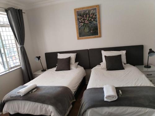 two beds sitting next to each other in a room at Paulshof Guesthouse - Kingsway B&B in Sandton