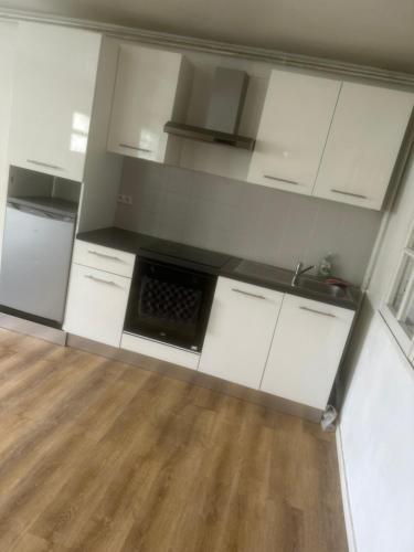 une cuisine vide avec des placards blancs et un évier dans l'établissement Le Aulnay, à Aulnay-sous-Bois