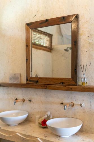 a mirror on a wall above two sinks in a bathroom at Mr Kahawa in Paje