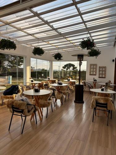 a dining room with tables and chairs and windows at Pousada Villa Dolce Amore - Boutique Hotel in Campos do Jordão