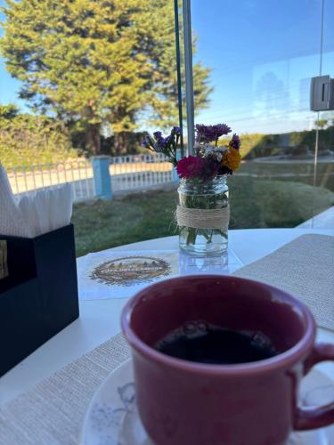 a cup of coffee on a table with a vase of flowers at Pousada Villa Dolce Amore - Boutique Hotel in Campos do Jordão