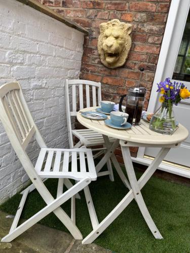 a white table and two chairs sitting next to a building at Award Winning Elegant luxurious refurbished meticulous 3 Bed in Alderley Edge