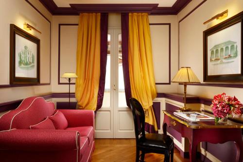 a living room with a red chair and a desk at Santa Maria Novella - WTB Hotels in Florence