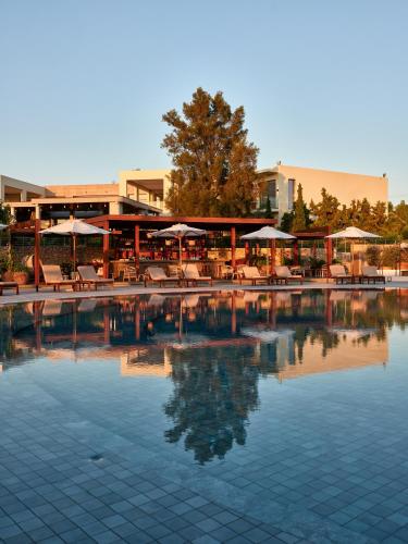 a swimming pool with chairs and umbrellas in a resort at Port Royal Villas and Spa - Adults Only in Kolimbia
