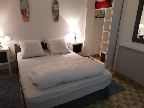 une chambre avec un lit avec des draps blancs et des oreillers dans l'établissement Studio pied dans l'eau Petite Plage de Domino pour 4 personnes, à Les Sables Vignier