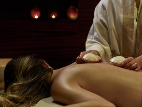 a woman laying on a massage table with a therapist at Port Royal Villas and Spa - Adults Only in Kolimbia