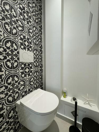 La salle de bains est pourvue de toilettes et de papier peint noir et blanc. dans l'établissement Apt moderne et luxueux a Cannes Res Miramar, à Cannes