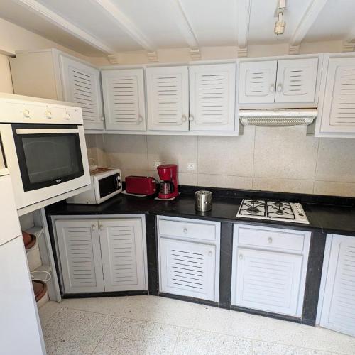 a kitchen with white cabinets and a stove and a microwave at Dar Ettaki Workation Riad Cité Portugaise Mazagan in El Jadida