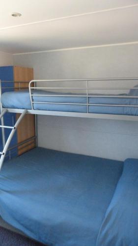 a bunk bed in a room with blue sheets at Parque de Campismo Orbitur Sagres in Sagres