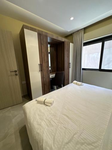 a bedroom with a large white bed with a desk at Chic Apartments For Rent ave0-6 in Amman