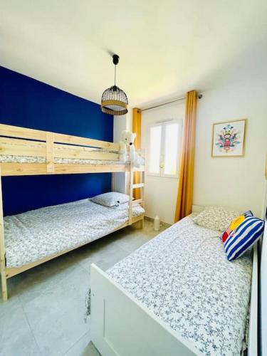une chambre avec deux lits superposés et un mur bleu dans l'établissement Maison haut de gamme dans le golf de pont royal, à Mallemort