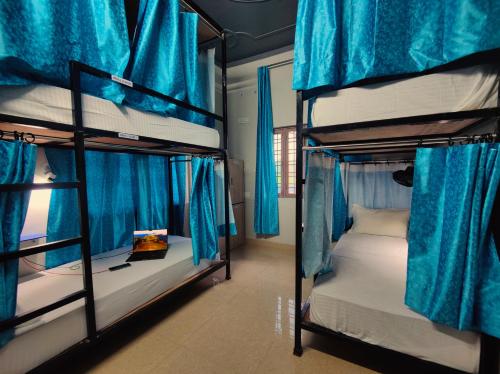 two bunk beds in a room with blue curtains at Hoztel Jollygrrant Doon in Rāni Pokhri