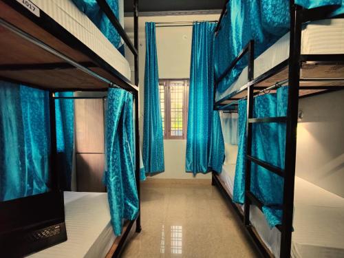 a room with bunk beds with blue curtains and a window at Hoztel Jollygrrant Doon in Rāni Pokhri