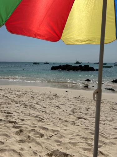 a colorful umbrella on a beach with the ocean at Coastal View Apartments in Grand Baie