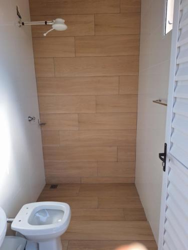 a bathroom with a toilet and a wooden floor at Casa acolhedora, bem aconchegante com piscina. in Brotas