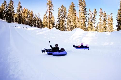 a group of three people riding on a snowboard in the snow at The Bridges 102 in Mammoth Lakes
