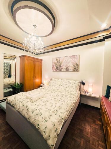 a bedroom with a large bed with a chandelier at Casa de Nuevo Comfy, Central and Netflix in Cagayan de Oro