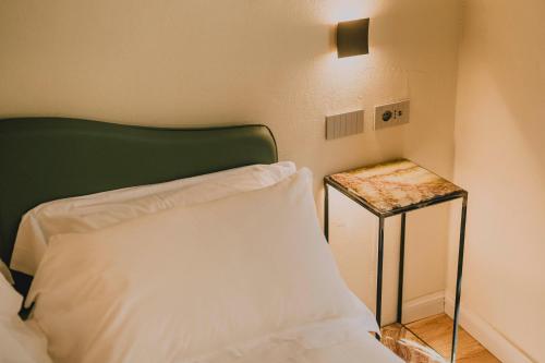a bed with a green headboard next to a side table at Palazzo Patrizi Suites & Spa in Siena