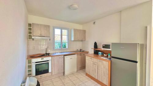 une cuisine avec des armoires en bois et un réfrigérateur dans l'établissement Maison 8min de Disney 6 couchages, à Magny-le-Hongre