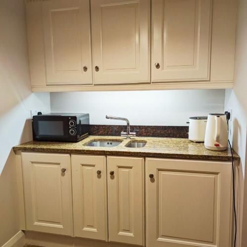 a kitchen counter with a sink and a microwave at Coachman's Loft in Kells