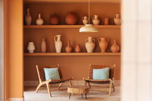 a room with two chairs and vases on shelves at Apartamentos Punta Rasa in Cala Saona
