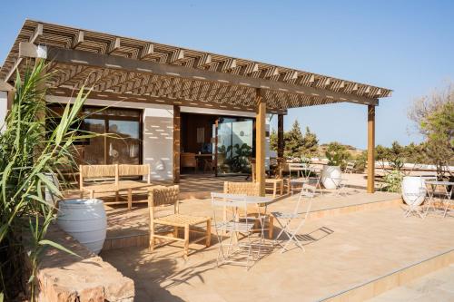 a patio with tables and chairs under a pergola at Apartamentos Punta Rasa in Cala Saona