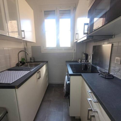 une petite cuisine avec un évier et une fenêtre dans l'établissement Appartement cosy proche Paris, à Colombes