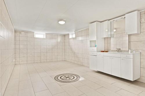 baño con armarios blancos y suelo de baldosa. en Luksuriøs enebolig ved Granåsen til Ski-VM 2025, en Trondheim