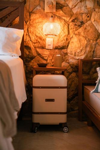 a luggage cart in a bedroom with a rock wall at Saona Bangalôs Taíba in Taíba