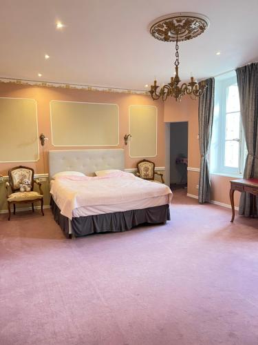 une chambre avec un grand lit et un lustre dans l'établissement Chateau de la Brillere, à Verrières