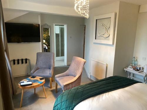 a bedroom with a bed and two chairs and a table at The Fossil Tree Hotel in Blackpool