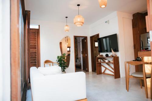 a living room with a white couch and a tv at Saona Bangalôs Taíba in Taíba