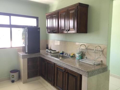 a kitchen with a sink and a black refrigerator at Hotel Lleras - Aparthotel in David