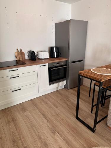 une cuisine avec des armoires blanches et un réfrigérateur en acier inoxydable dans l'établissement Superbe appartement vannetais, à Vannes