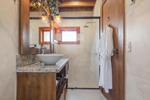 ein Badezimmer mit Waschbecken, Spiegel und Dusche in der Unterkunft Cabana Gelb Hütte Vila Germânica by Achei in Nova Petrópolis