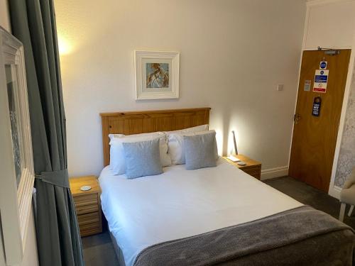 a bedroom with a large white bed with blue pillows at The Fossil Tree Hotel in Blackpool