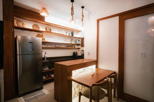 a kitchen with a wooden table and a refrigerator at Saona Bangalôs Taíba in Taíba