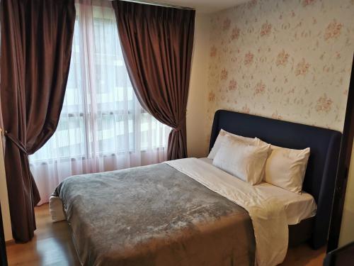 a bedroom with a bed and a window with curtains at Centrio Phuket C3 in Ban Rangeng